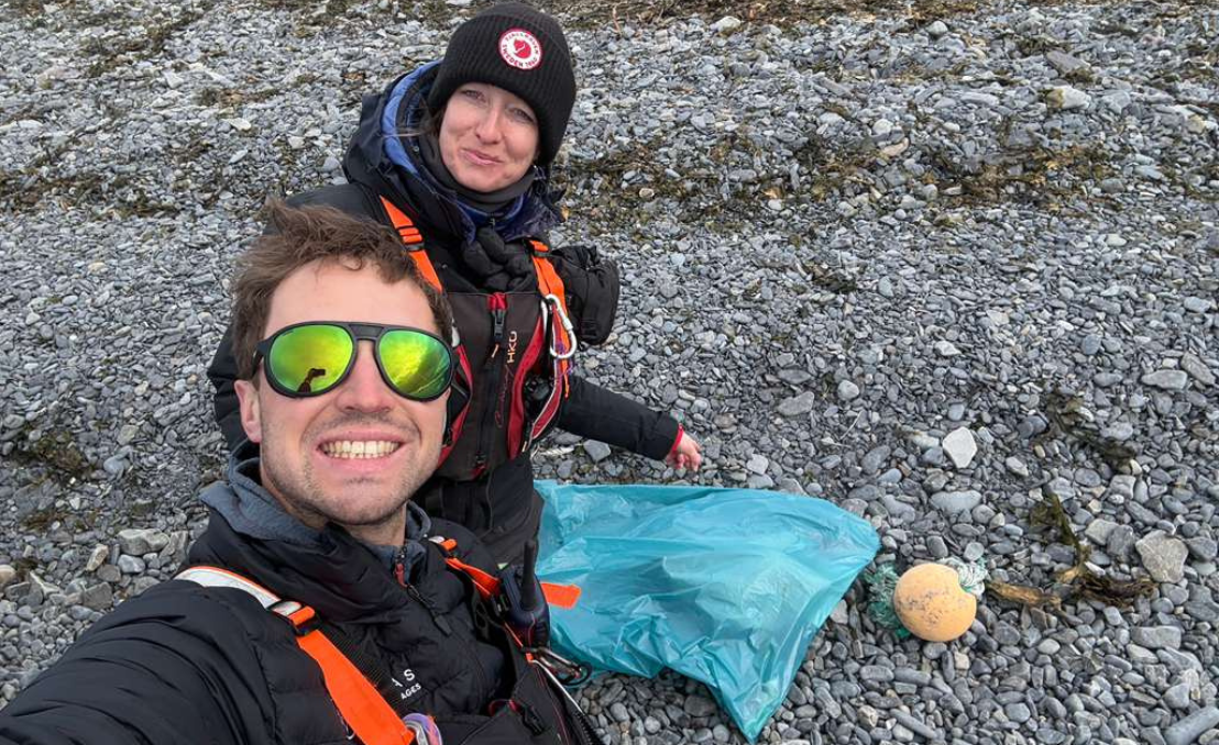 Miembros del equipo durante una limpieza costera en Svalbard con una bolsa de residuos recogidos